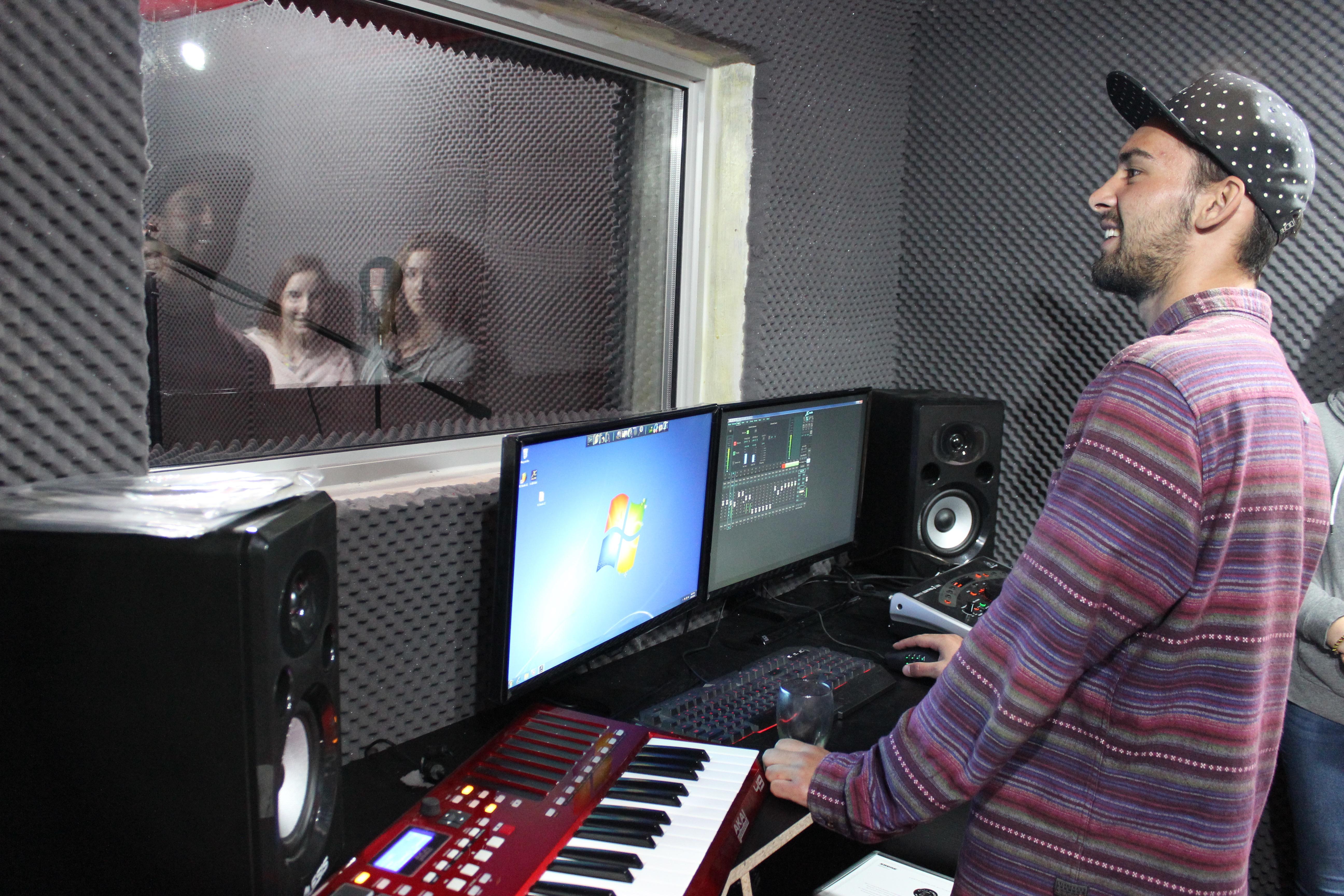 Male Projects Abroad Music Production Intern records vocals in a recording studio during a Music Production Internship in South Africa. Male Music Production Intern records vocals of a local group during his placement in Cape Town, South Africa.
